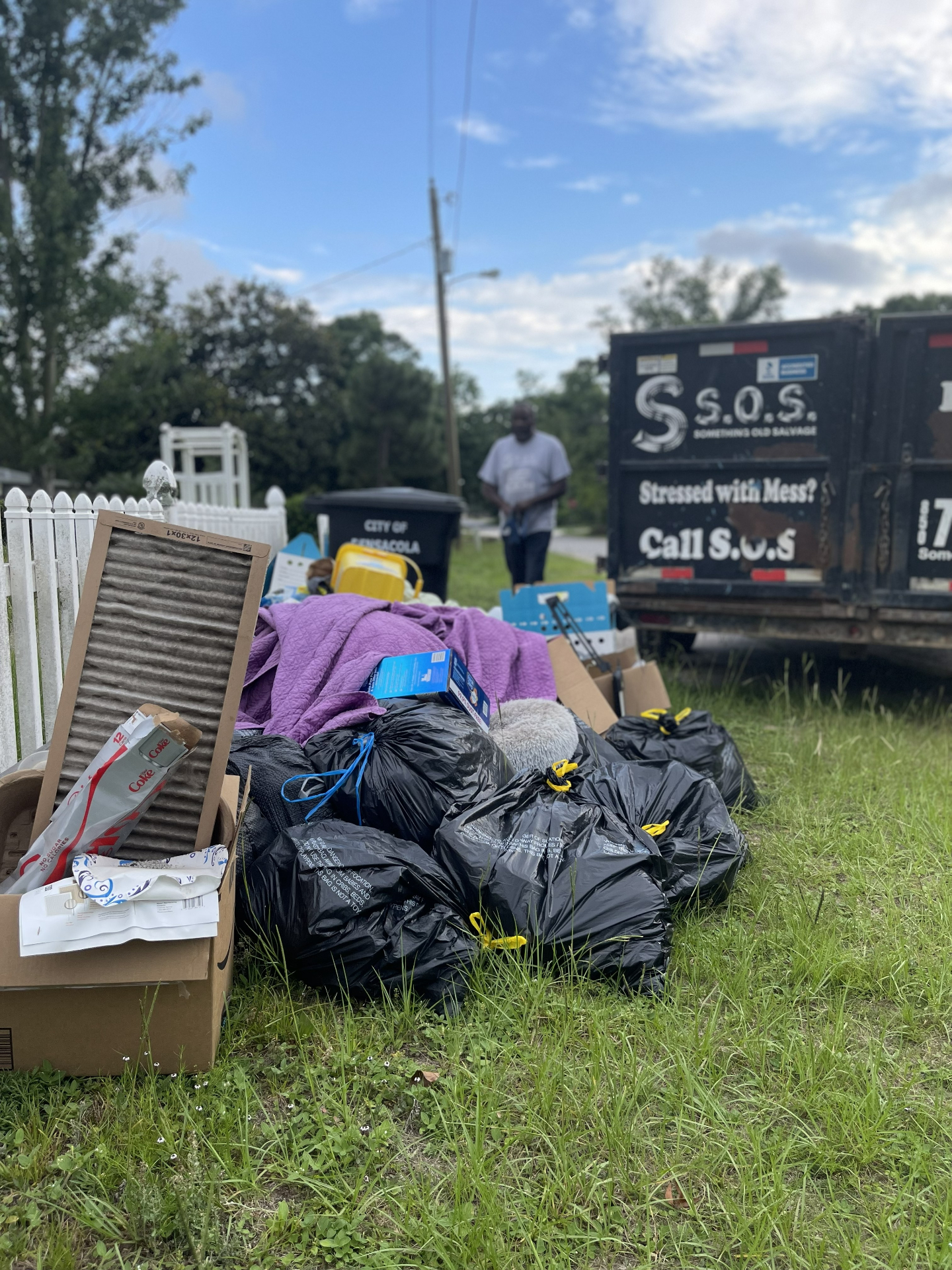 SOS Junk Removal truck next to a curbside junk pile